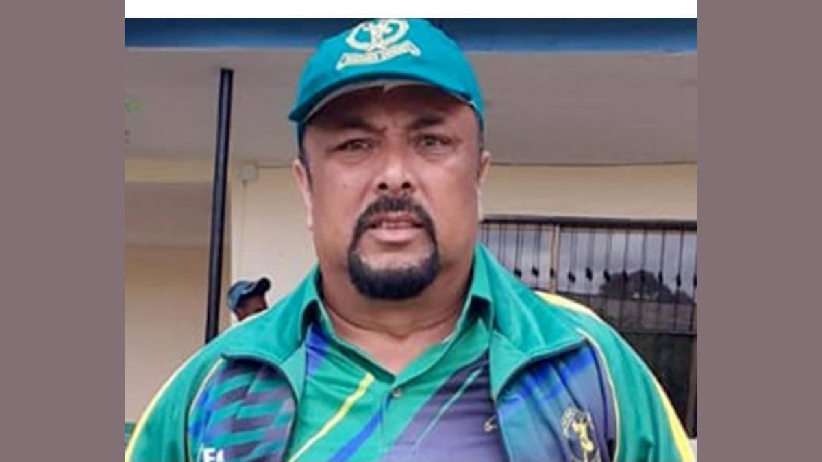 Yahya Jiwa, a cricket coach, standing on a cricket field, wearing a coaching outfit and holding a cricket bat, representing his remarkable journey from Surat, Gujarat to Eswatini as he takes on the coaching role for the Under-19 and Women's cricket teams.